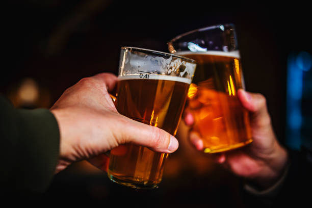 Two friends hands toasting with glasses of craft beer at the pub or bar. taproom Two friends hands toasting with glasses of craft beer at the pub or bar. taproom india pale ale photos stock pictures, royalty-free photos & images