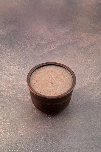 Tasty and Healthy Sweet Ragi Dates Malt or Red Quinoa Porridge on brown background. Indian food.