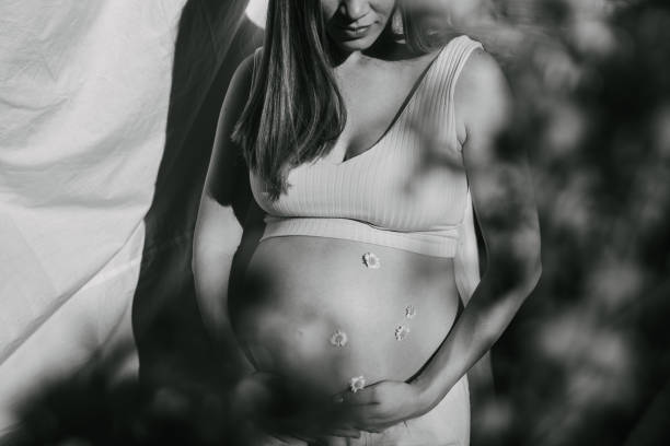 Close-Up Of Pregnant Woman Touching Belly Against White Background