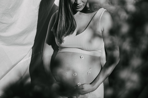 One woman, beautiful pregnant woman touching her belly. Black and white.