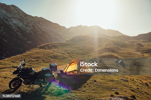 istock Camping with motorcycle and tent on lawn in mountains 1438012468