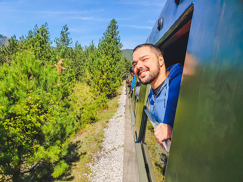 Smiling man standing on the train window while travelling