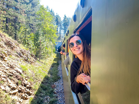 Smiling woman standing on the train window while travelling