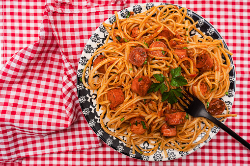 Hearty italian pasta dish with tomato sauce and sausage with sauce on a rustic table.