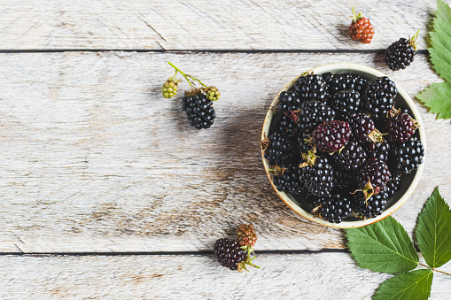 Blackberries on wooden table, fresh blackberry in bowl, overhead view, copy space