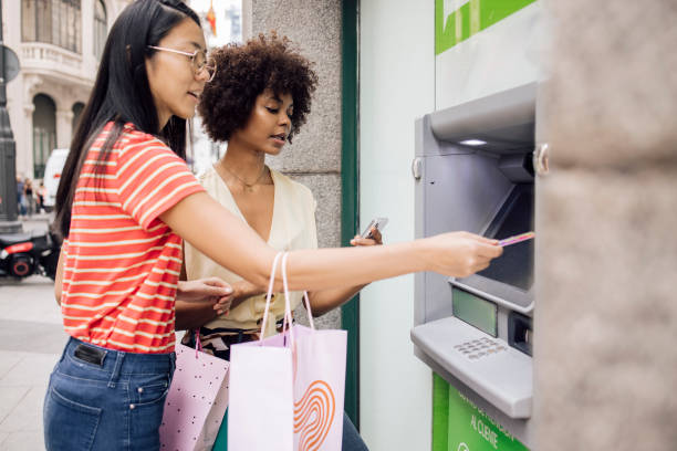 istock Two girlfriends in Madrid taking the money from ATM 1438023061