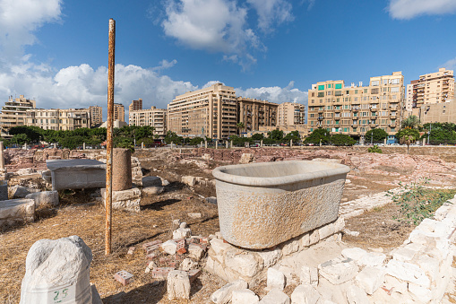Ancient Roman artifacts at the excavations against the background of modern houses in the city Alexandria. Egypt. Attractions.