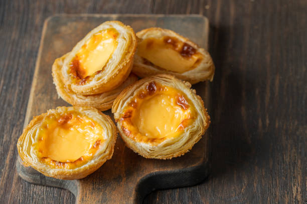 istock Pasteis de Belem,  portuguese egg tart pastries  on wooden cut board. Copy space 1438023945