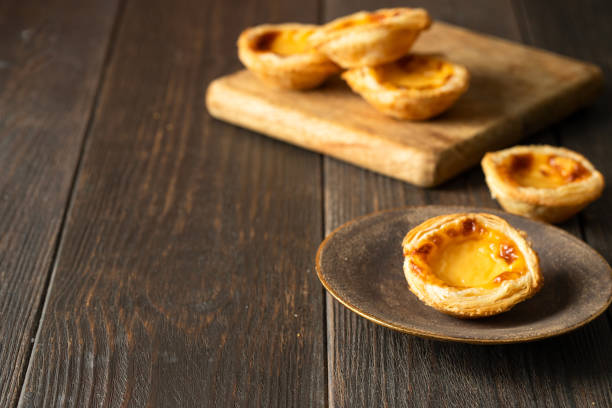 istock Pasteis de Belem, portuguese egg tart pastries in the brown plate   on wooden table.Copy space 1438023946