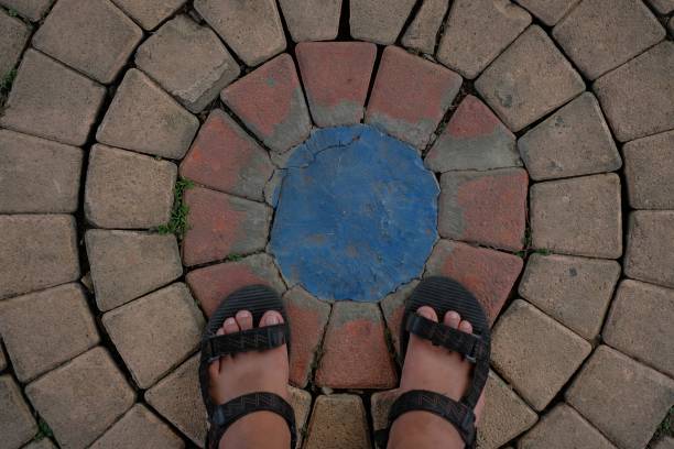 a pair of feet wearing sandals on circular bricks in orange and blue color