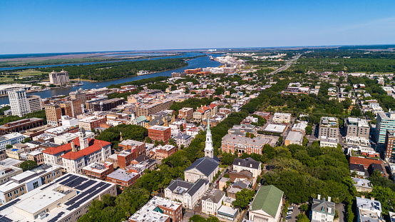 Aerial view of the Historic District in Downtown Savannah, Georgia, with  Independent Presbyterian Church in the foreground, and a distant view of the Savannah River in the backdrop.