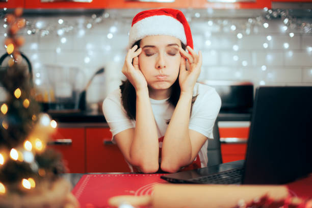 donna stressata che controlla il suo laptop per una ricetta video online - holiday emotional stress christmas santa claus foto e immagini stock