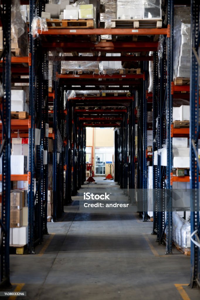 Empty hall at a distribution warehouse Empty hall at a distribution warehouse with merchandise on shelves on the sides Freight Transportation Stock Photo