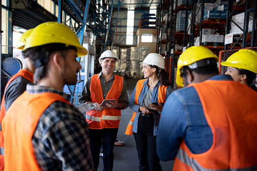 Business manager talking to a group of workers in a staff meeting at a distribution warehouse