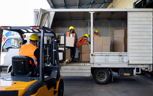 Group of Latin American Workers unloading boxes from a truck while working for a freight transportation company