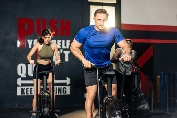 gruppo di giovani atleti che fanno esercizio insieme nella palestra fitness. attraenti sportivi attivi e sportivi si allenano insieme pedalando su una macchina da bici per l'assistenza sanitaria e il benessere nello stadio. - spinning health club instructor gym foto e immagini stock