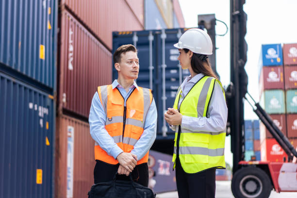 istock Caucasian business man and woman worker working in container terminal. Attractive engineer people processes orders and product at warehouse logistic in cargo freight ship for import export in harbor. 1438035627