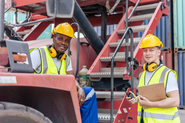 istock African American and Caucasian man worker work in container terminal. Attractive handsome male laborer stand and talking on forklift after process orders at warehouse logistic in cargo freight ship. 1438035629