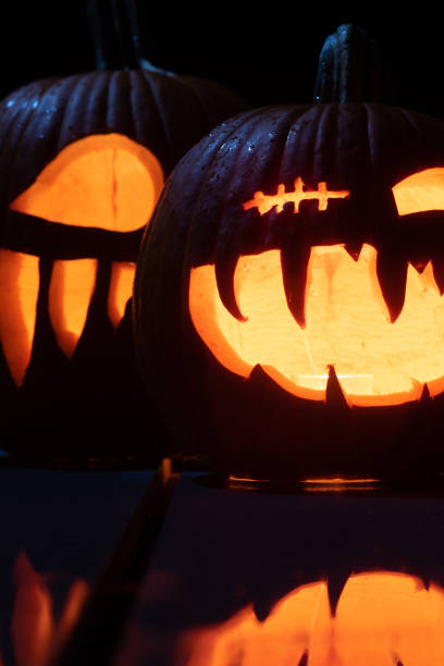 istock Twilight Jack O'Lanterns - Carved Pumpkins at Night - Scary Halloween Decorations - Close Up 1438036524
