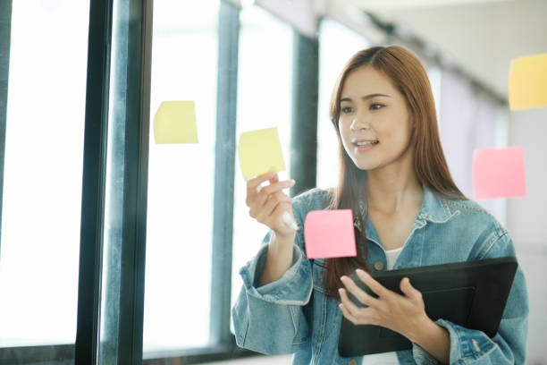 istock Young female student writing study plans on post-its on glass wall. 1438039423
