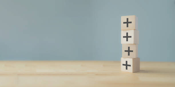 istock Plus sign in wooden cubes stacking. Positive things; additional, added value, benefits, improve, develop, growth mindset, positive thinking, motivation, increase, opportunities, and emerging market. 1438040432