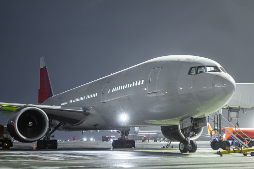 Wide body passenger airplane at the airport apron at winter night