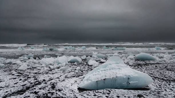 Icebergs Iceland Diamond Beach Jökulsárlón Winter Panorama Jokulsarlon Black Beach Snow covered Iceberg on Iceland Jökulsarlon Lagoon Diamond Beach in Winter Panorama. View over the Black Beach - Diamond Beach with snow covered stranded Iceberg from the glacier lake lagoon of Jökulsarlon under overcast snowy winter sky. Stiched Canon R5 XXL Panorama. Diamond Beach, Jokulsarlon, Vatnajökull National Park, Route 1, Southeast Iceland, Iceland, Nordic Countries, Northern Europe jokulsarlon stock pictures, royalty-free photos & images