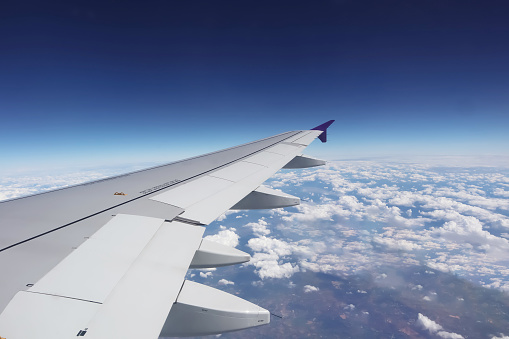 Aerial view from window of aircraft show aircraft wing and engine with horizon deep blue sky above all white clouds for transportation and travel airline business presentation background.