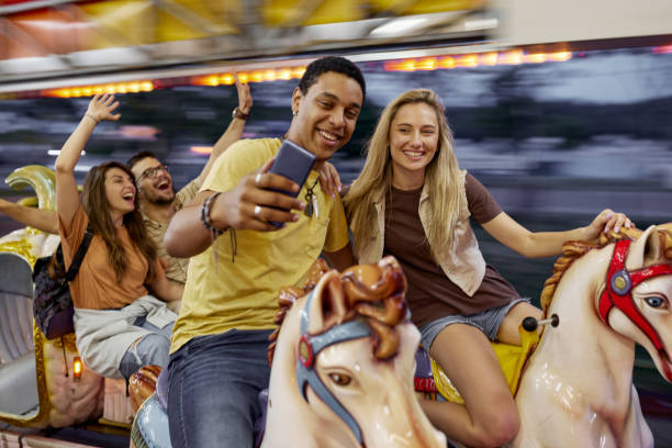 istock Happy couple taking a selfie during carousel ride at amusement park. 1438065778
