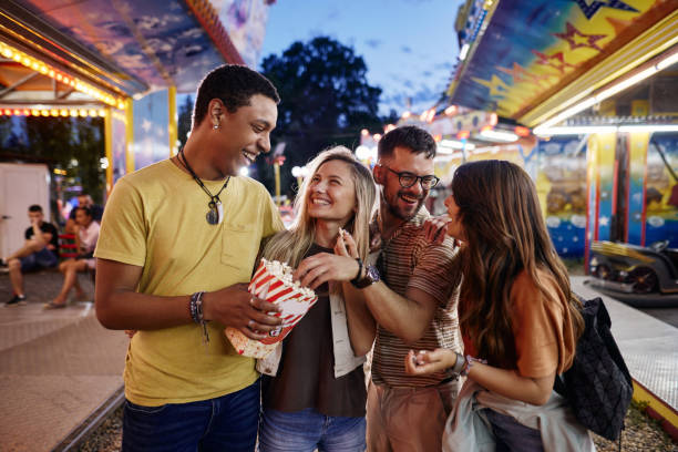 istock Happy couples talking while eating popcorn at amusement park. 1438065853