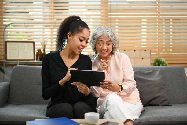 istock Grownup daughter teaching interested elderly mother how to use a tablet or shows some application. Elderly, technology concept. 1438067676