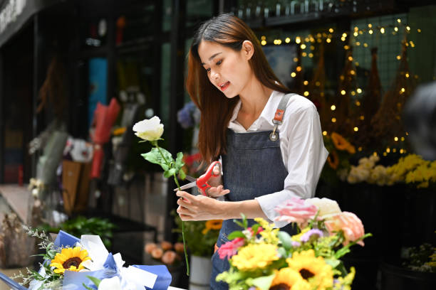 istock Focused female florist cutting branches, creating beautiful bouquet with with different flowers her floral shop. 1438067769