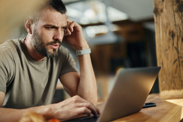 istock Worried man on the phone using laptop at home. 1438069265