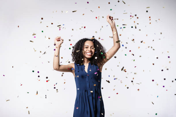 istock Joyful woman laughing, dancing and has fun with falling confetti. Enjoying life, celebration concepts 1438075247