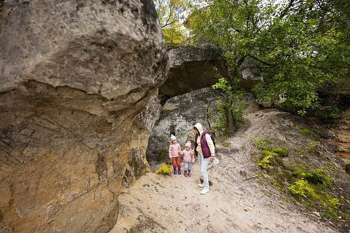 Mother with two daughters explore limestone stone cave at mountain in Pidkamin, Ukraine.