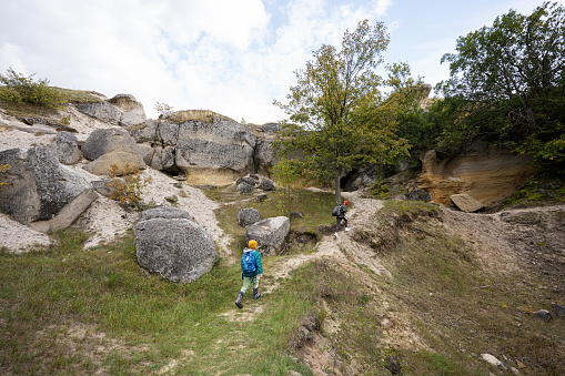 Two brothers wear backpack explore limestone stone caves at mountain in Pidkamin, Ukraine.