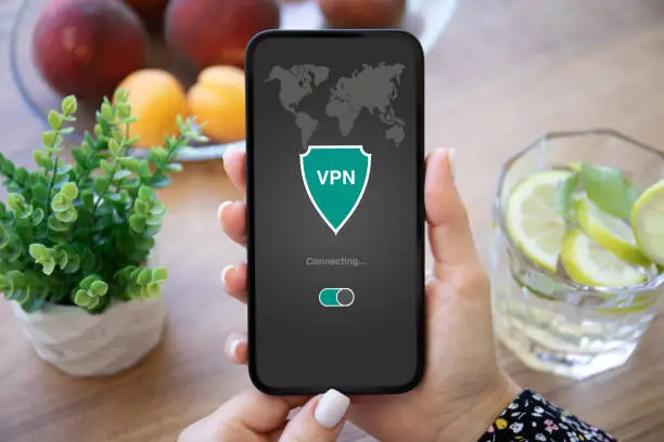 Photo of female hand holding phone with app vpn on the screen