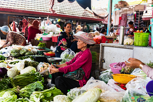 Kampot, Cambodia – August 07, 2019: A woman trader selling vegetables and fruit at the  A woman trader selling vegetables and fruit at the Kampot fresh market