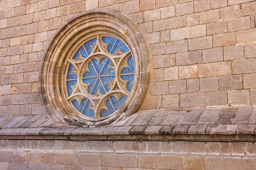 A rose window, gothic architecture with a shield over the stained glass.
