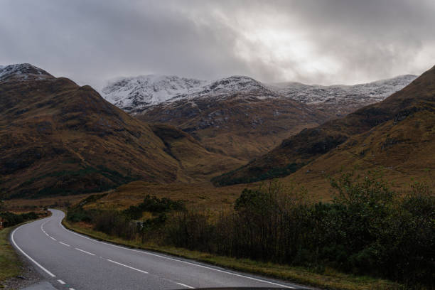 istock Majestic view of a curvy paved road going through a mountain range with snow-covered peaks 1438080065