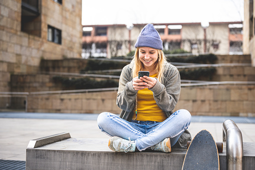 portrait of a young smiling teenager girl using smartphone to text message and surfing the internet, generation z lifestyle