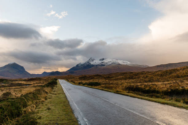 istock Paved road winding through a dry grass-covered landscape with a mountain range on the horizon 1438080202