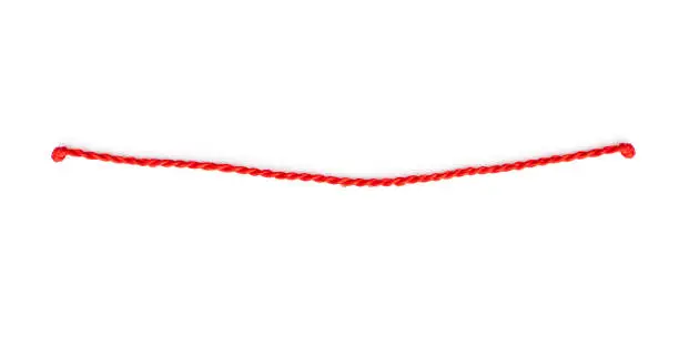 Photo of Thin red string or rope with knots isolated on white