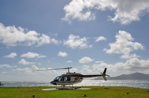 La Digue Islan, Seychelles – August 03, 2010: Helicopter on landing on a tropical island with grass helipad