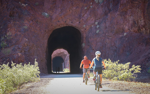 Boulder City, Nevada, United States – May 09, 2018: Two bicyclists pedal down the Historic Railroad Trail in Boulder City toward the shores of Lake Mead.