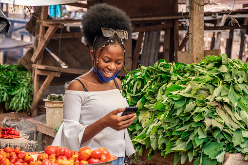 A pretty african lady using her phone in a market.