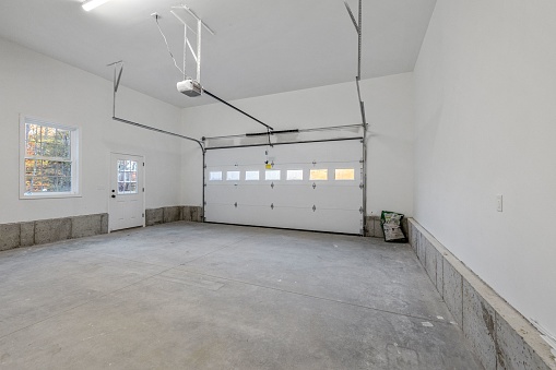 An indoor shot of a newly constructed garage with white walls and gray floor