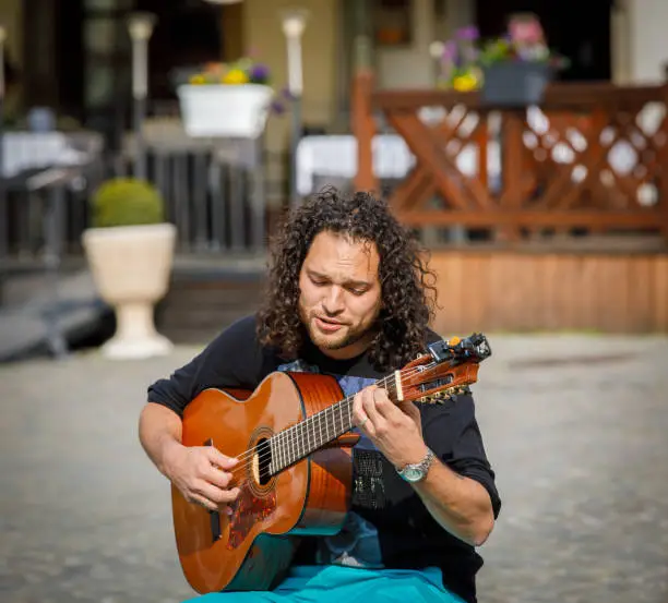 Photo of A street musician plays the guitar, entertains people in the city square.