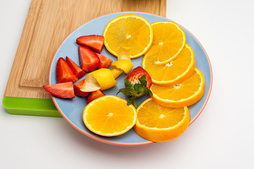 A high angle shot of a plate with oranges and strawberries