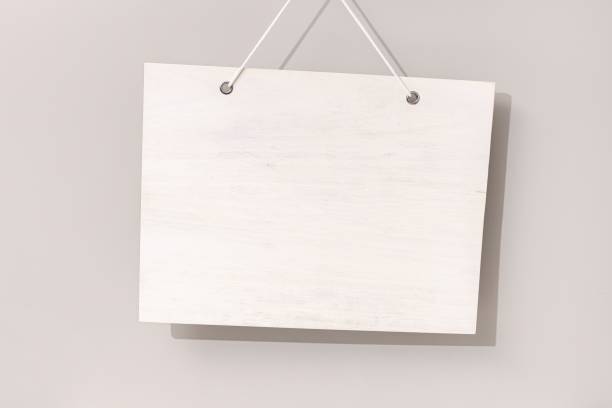 istock Blank white wooden sign hanging on beige background 1438082801